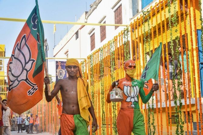 BJP workers holding their party flag walk along a decorated street, on the eve of the groundbreaking ceremony of the Ram Mandir, in Ayodhya, on Tuesday. Photograph: PTI Photo